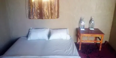 a bedroom with a bed and a table with two bottles on it at Titanic hôtel restaurant & désert excursions lac irik in Foum Zguid