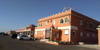a building with a car parked in a parking lot at HOTEL LA POMME ZAIDA in Zaida