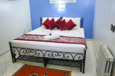 a bedroom with a bed with red pillows at HOTEL LA POMME ZAIDA in Zaida