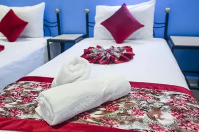 two beds with white towels and red pillows at HOTEL LA POMME ZAIDA in Zaida