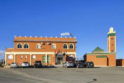 a hotel with cars parked in front of a building at HOTEL LA POMME ZAIDA in Zaida