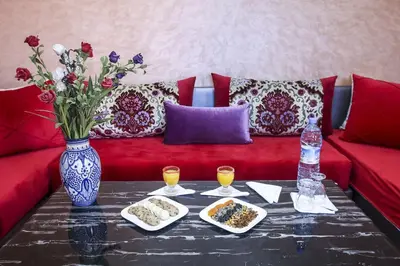 a red couch with a table with food on it at HOTEL LA POMME ZAIDA in Zaida