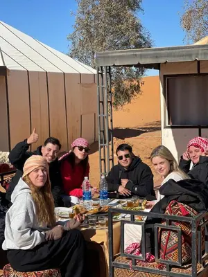 a group of people sitting at a table in the desert at Riad Akabar Merzouga in Merzouga