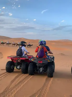a group of people riding on atvs in the desert at Riad Akabar Merzouga in Merzouga