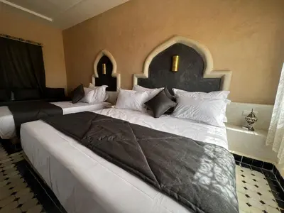 a bedroom with two large beds in a room at Riad Akabar Merzouga in Merzouga