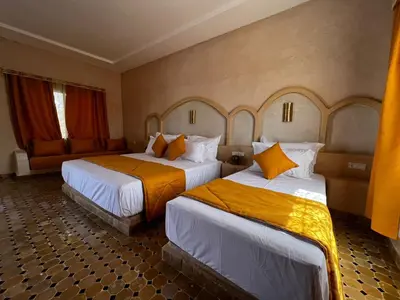 a hotel room with two beds with orange pillows at Riad Akabar Merzouga in Merzouga