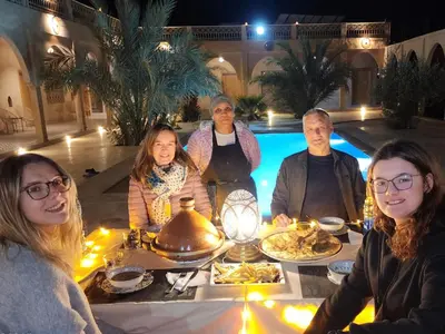 a group of people sitting at a table with food at Riad Akabar Merzouga in Merzouga