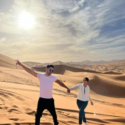 a man and a woman walking in the desert at Local Luxury Camp in Merzouga