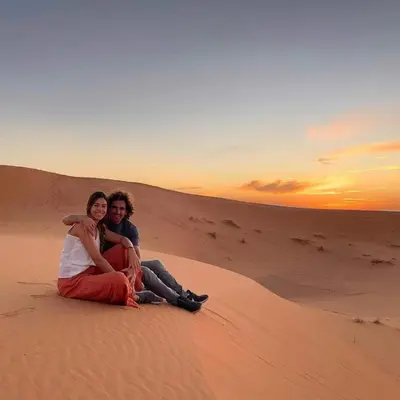 a man and a woman sitting in the desert at Local Luxury Camp in Merzouga