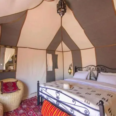 a bedroom with a bed and a chair in a room at Local Luxury Camp in Merzouga
