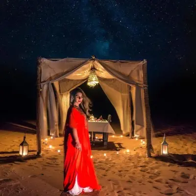 a woman in a red dress standing in front of a tent at Local Luxury Camp in Merzouga