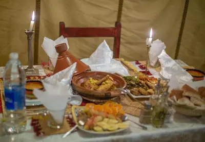 a table with plates of food and candles on it at Sahara Relax Camp in Merzouga