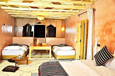 a room with three beds and a table in it at Chateau Imilchil in Imilchil