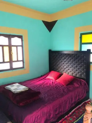 a bedroom with a bed with purple sheets and a window at Gite La belle vue Timichi in Timichi