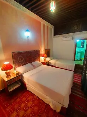 a hotel room with two beds and two lamps at famille fahym in Fès