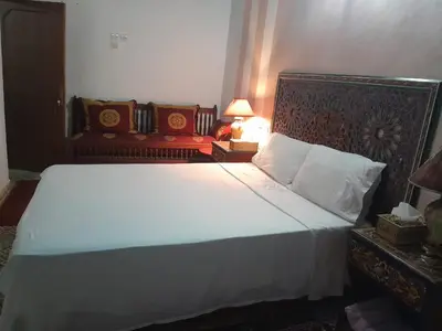 a bedroom with a large white bed and two chairs at famille fahym in Fès