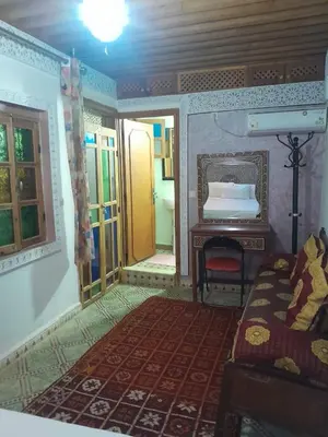 a bedroom with a bed and a table and a mirror at famille fahym in Fès