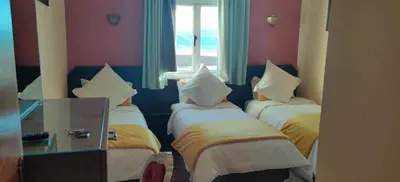 a room with three beds with yellow and white sheets at Auberge Tourtite in Ifrane