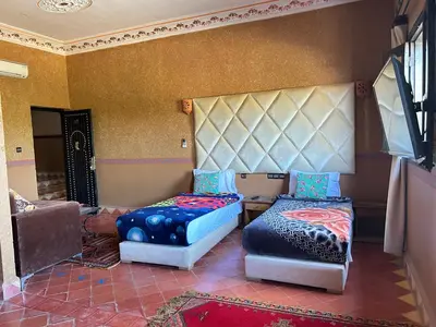 a room with two beds and a chair in it at Hotel Zagour - Luxury hotel in Zagora in Zagora