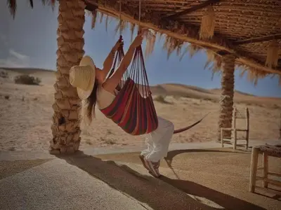 a woman in a hammock in the desert at Khadija Desert Camp in Merzouga