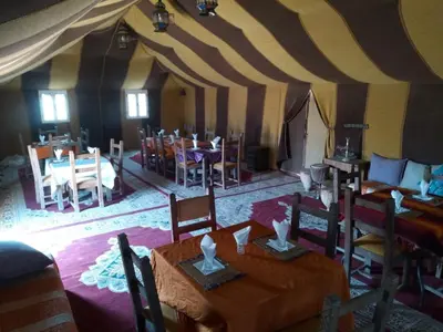 a dining room with tables and chairs in a tent at Khadija Desert Camp in Merzouga