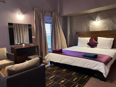 a hotel room with a bed and a chair at Kasbah Tifoultoute in Ouarzazate