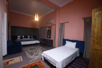 a bedroom with two beds and a living room at Kasbah Tifoultoute in Ouarzazate