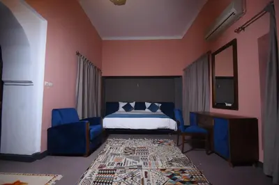 a bedroom with a bed and two blue chairs at Kasbah Tifoultoute in Ouarzazate