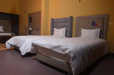 a bedroom with two beds with white sheets and pillows at Kasbah Tifoultoute in Ouarzazate