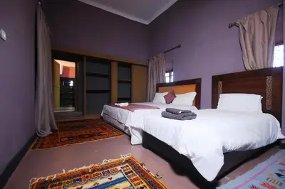 a bedroom with two beds with white sheets at Kasbah Tifoultoute in Ouarzazate