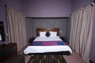 a bedroom with a large bed with white sheets and pillows at Kasbah Tifoultoute in Ouarzazate