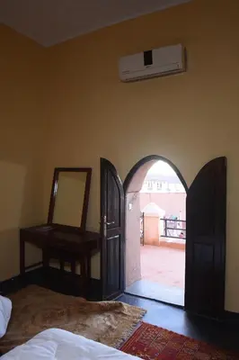 a bedroom with an open door with a mirror and a bed at Kasbah Tifoultoute in Ouarzazate