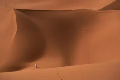 a person standing in the middle of a desert at Desert Erg Chigaga Lodge in El Gouera