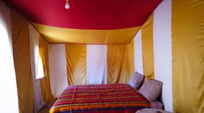 a bedroom with a bed with a red and yellow ceiling at Desert Erg Chigaga Lodge in El Gouera