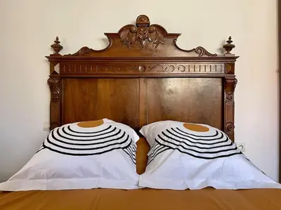 a bed with a wooden head board and two pillows at Magnifique villa - 5 chambres - Ifrane in Ifrane