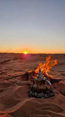 a tea pot sitting on top of a fire in the desert at Sahara Authentic Berber Camp in Mhamid