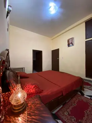 a bedroom with a red bed and a table with a lamp at Villa familys in Fès