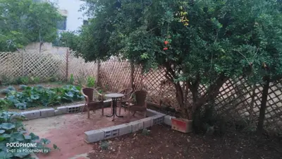a table and chairs under a tree next to a fence at Villa familys in Fès