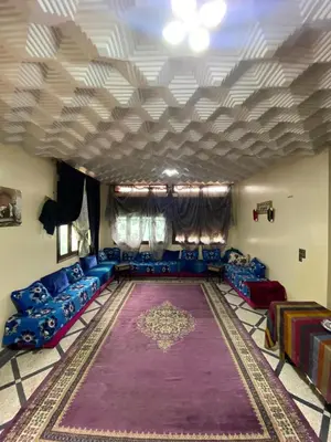a living room with blue couches and a large rug at Villa familys in Fès