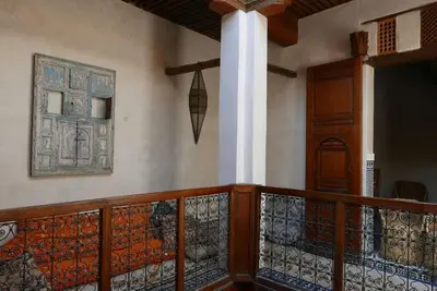 a room with a balcony with a door and a wall at House in the old Medina of Fez in Fès al Bali
