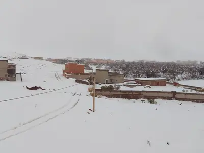 a snow covered city with buildings and a street at Chez L'habitant Brahim kanih in Anzel