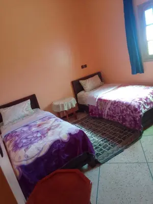 a bedroom with two beds and a table and a window at Chez L'habitant Brahim kanih in Anzel