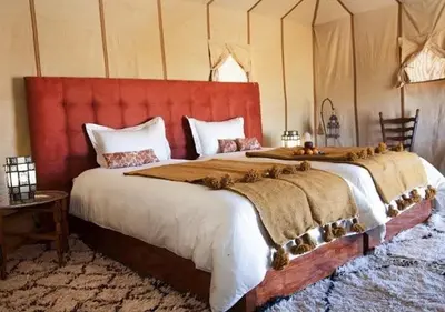 a bedroom with a large bed with a red headboard at Amazing Desert Luxury Camp in Merzouga