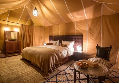 a bedroom with a bed and a table in a tent at Amazing Desert Luxury Camp in Merzouga