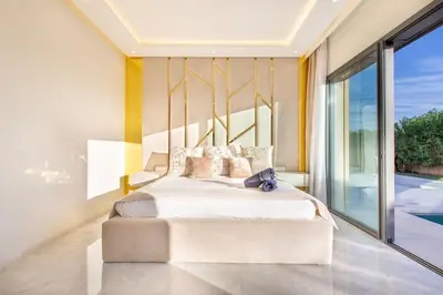 a bedroom with a large bed and a large window at Villa Hawai, ss vis à vis avec espace de sport , piscine Chauffée in Marrakech