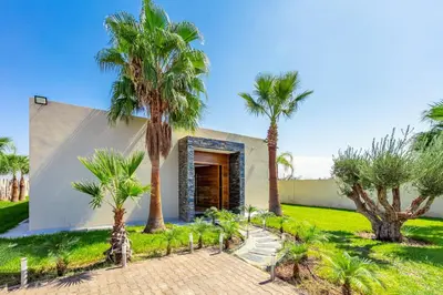 a house with palm trees in front of it at Villa Hawai, ss vis à vis avec espace de sport , piscine Chauffée in Marrakech