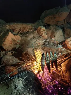 a grill with four people standing next to a fire at Appartement Ain Asserdoun in Beni Mellal