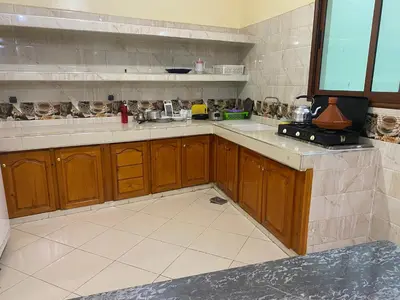 a kitchen with wooden cabinets and a tile floor at Appartement Ain Asserdoun in Beni Mellal