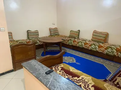 a room with two beds and a table and chairs at Appartement Ain Asserdoun in Beni Mellal