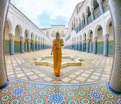 a woman in a yellow dress walking through a building at Youssef in Fès